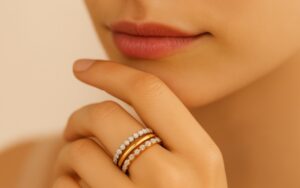 Close-up of a woman's hand wearing three stacked rings in white, yellow, and rose gold one plain gold and two set with diamonds. Vintage eternity