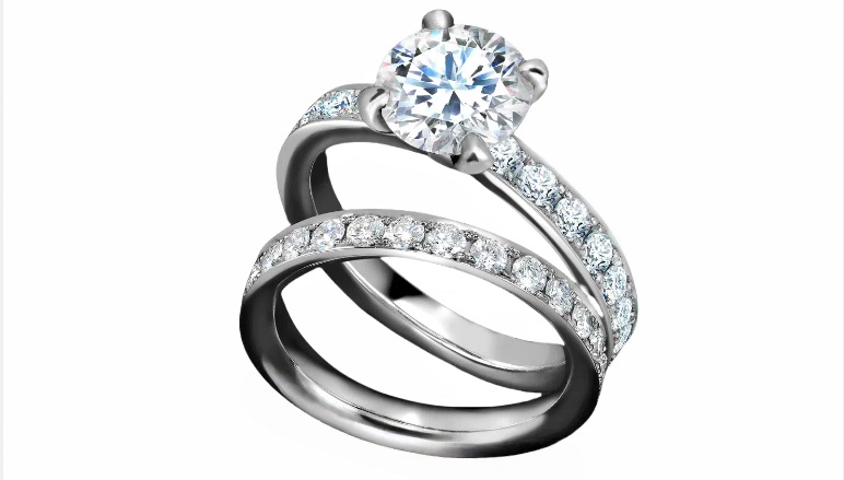 Matching platinum diamond engagement and wedding ring. Round brilliant cut diamond engagement ring with claw set centre and pavé set diamond shoulders, paired with a matching pavé set diamond wedding band
