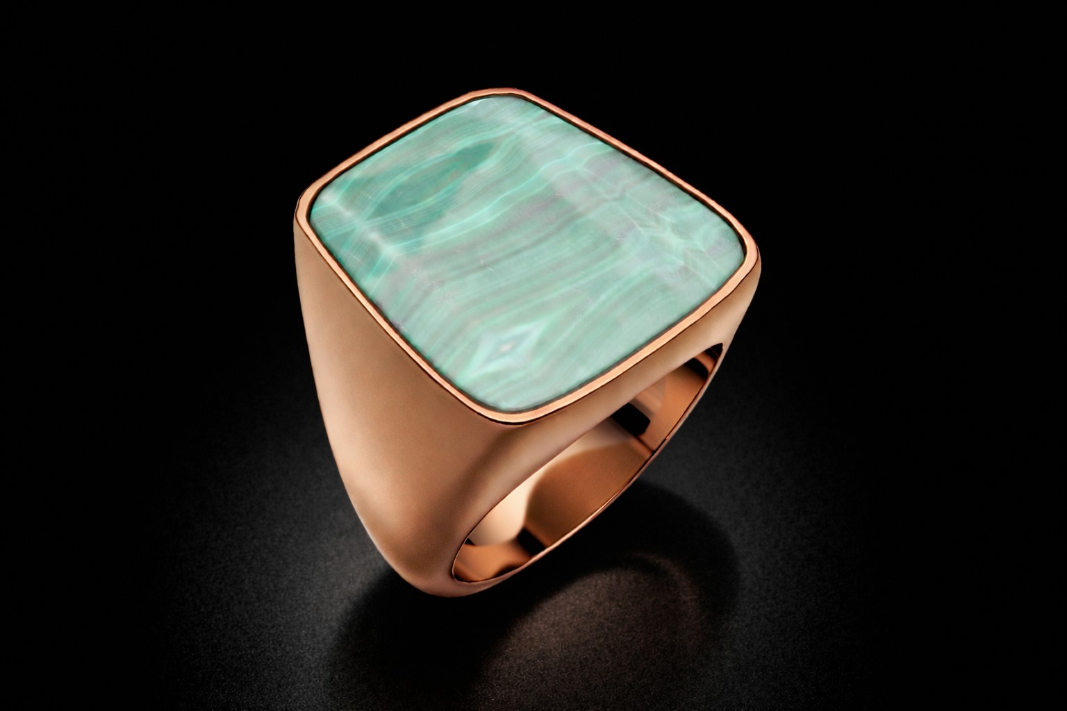 Bespoke 18ct rose gold malachite statement ring photographed on a black background in Hatton Garden.
